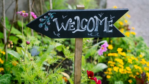 Small wooden sign that reads 'Welcome' in a flower bed at SIzergh.